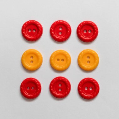 Beyaz zemin üzerinde birçok farklı kırmızı ve sarı plastik düğmeler.