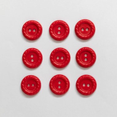 Beyaz arka planda kırmızı plastik düğmeler. Dikiş aletleri. Üst görünüm.