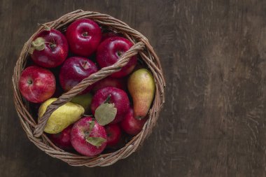 Ahşap bir arka planda hasır sepetteki organik kırmızı elmalar. Üst Manzara. Boşluğu kopyala.