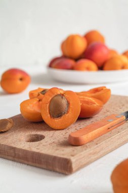 Kesme tahtasındaki kayısı dilimleri. Taze organik kayısılar. Kayısı soyma işlemi.