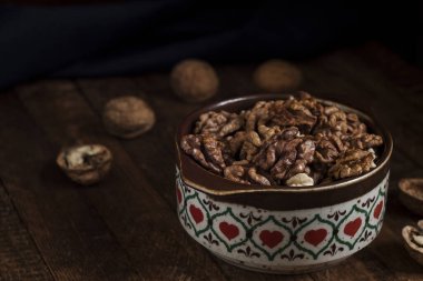 Ahşap arka planda seramik kasede kurumuş ceviz çekirdekleri..