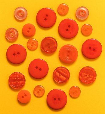 Sarı arka planda farklı boyutlarda bir sürü turuncu düğme var. Üst görünüm.