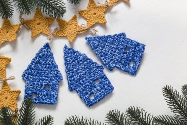 El yapımı tatiller. Tığ işi mavi Noel evleri ve beyaz arka planda sarı yıldız çelenkleri. Üst Manzara. Boşluğu kopyala.