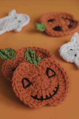 Turuncu arka planda düz örgü ören Cadılar Bayramı balkabakları.