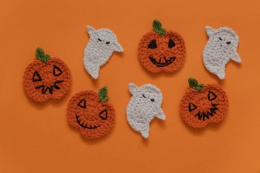 Turuncu arka planda Cadılar Bayramı tığ işi dekoru. El yapımı portakal kabakları ve beyaz hayalet..