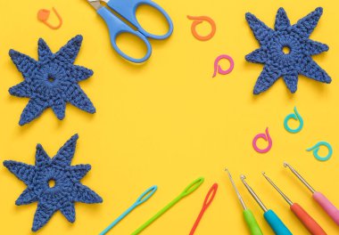 Sarı zemin üzerinde mavi kar taneleri olan parlak renkli tığ işi aletler. Üst Manzara. Boşluğu kopyala.