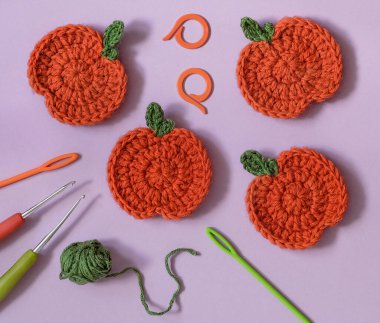 Örgü balkabağı ve tığ işi aksesuarlarla mor arka plan. Üst Manzara. Tığ işi konsepti.