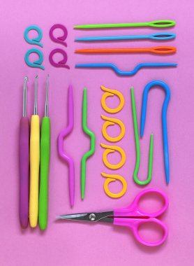 Pembe arka planda parlak renkli örgü ve örgü aletleri. Düz yatıyordu.