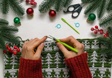 Kadın elleri Noel yorganı örüyor köknar ağacı desenli.