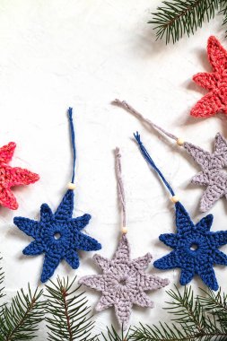 El yapımı örgü dekoru. Beyaz arka planda gri, mavi, kırmızı tığ işi yıIbaşı ağacı şekilli oyuncaklar. Boşluğu kopyala.