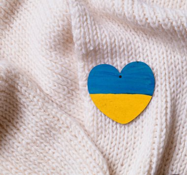 Ukrayna 'daki savaşı bitirme kavramı. Tahta kalp, Ukrayna bayrağını beyaz bir kumaşa bastırdı..