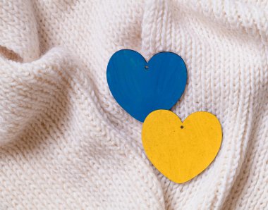 Ukrayna 'daki savaşı bitirme kavramı. Ukrayna bayrağı renginde iki tahta kalp. Mavi ve sarı kalpler beyaz bir kumaşta.