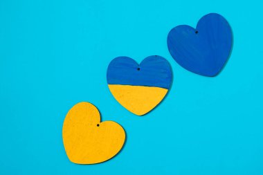 Mavi arka planda üç mavi sarı tahta kalp. Ukrayna bayrağı renginde kalpler. Ukrayna 'daki savaşı bitirmek.