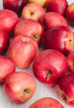 Beyaz ahşap masada bir sürü taze kırmızı elma. Sağlıklı yeme kavramı.