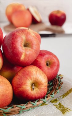 Güzel kırmızı elmalar beyaz bir masada hasır sepetin içinde kapanıyor..