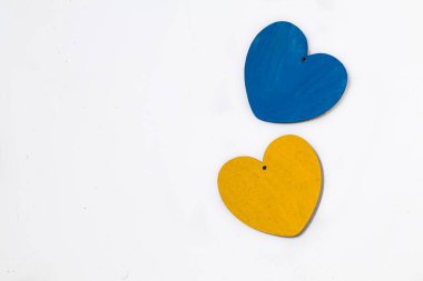 Beyaz arka planda iki ahşap mavi ve sarı kalp. Ukrayna bayrağı renginde kalpler. Ukrayna 'daki savaşı bitirmek.