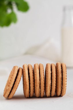 Tatlı sandviçli kurabiyeler ve beyaz arka planda bir bardak süt. Kahvaltı konsepti.