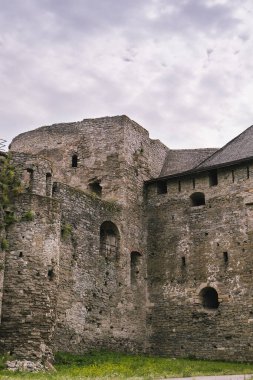 Antik kalede yıpranmış taş duvarlar ve yemyeşil yemyeşil, tarihi mimari ve kültürel öneme sahip sakin bir açık hava ortamında vurgu yapılıyor.