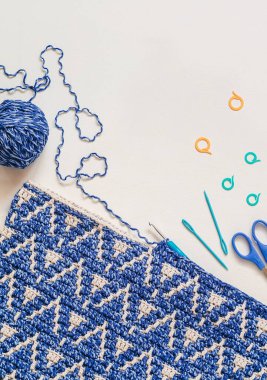 Beyaz arkaplanda mavi beyaz örülü mozaik kumaş oluşturma süreci. Üst Manzara. Boşluğu kopyala.