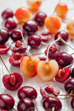 Beyaz arka planda kırmızı kirazların arasına yakın sulu sarı kiraz dilimi. Doğal tatlılar..