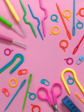 Pembe arka planda parlak modern tığ işi ve örgü aletlerinden yapılmış çerçeve. Üst Manzara. Boşluğu kopyala.