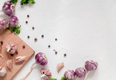 Mor sarımsak soğanı, karanfil, biber, maydanoz, beyaz arka planda kesim tahtası. Üst Manzara. Boşluğu kopyala.