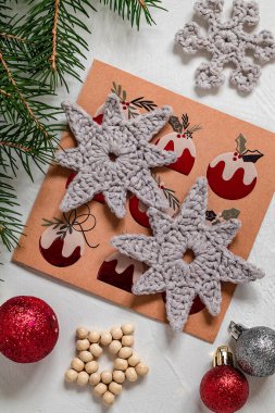 İki örgü yıldızlı Noel kompozisyonu, tebrik kartı, takı ve köknar dalı. Noel ağacı için el yapımı tığ işi oyuncaklar.