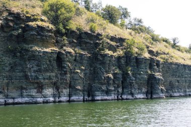 Dokulu kayalık uçurumlar ve yemyeşil yemyeşil, doğal güzellik ve sükuneti manzaralı bir nehir kıyısında sergiliyor. Bakota Körfezi, Dinyester Nehri, Ukrayna