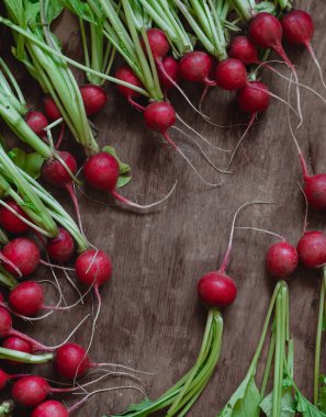 Ahşap zemin üzerinde yeşil yaprakları olan bir sürü taze kırmızı turp..
