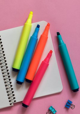 Renkli kalemler ve pembe arka planda bir defter. Okul konseptine dönelim..