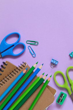 Okul kırtasiyesi ve mor arka planda iki defter. Üst Manzara. Boşluğu kopyala.