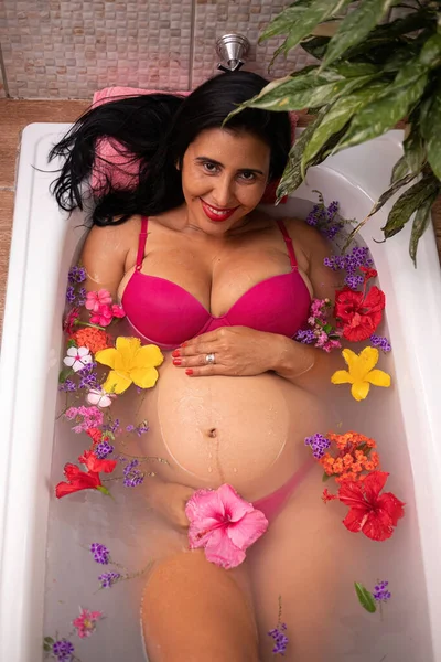 妊娠中の女性は 内湯で水と花で満たされた浴槽に横たわっています — ストック写真
