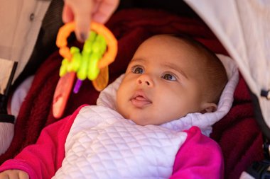 Bebek arabasında beyaz ve pembe elbiseli yeni doğmuş bir kızın yüzüne yakın çekim.