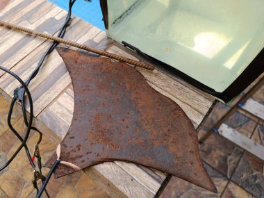 Pulluk diskinden kesilmiş çelik parçası akvaryumdaki elektroliz deneyinde kullanılmak üzere hazırlanıyor.