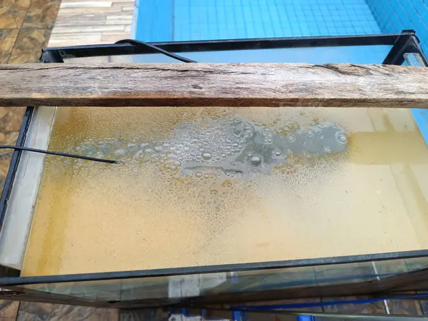 water surface in aquarium with bubbles and rust due to an experiment electrolysis process to remove rust from metals