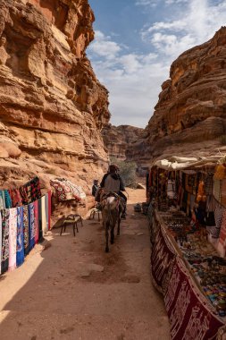 tourists visiting a rock at the grand canyon in petra, jordan in a beautiful summer day.