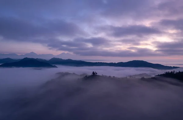 Cerkev Sveti Toma (St. Thomas Church) near kofja Loka, Slovenia. Foggy morning and sunrise, drone photo