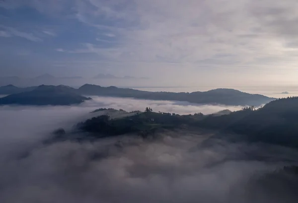 Cerkev Sveti Tomas (St. Thomas Church) near Skofja Loka, Slovenia. Foggy morning and sunrise, drone photo
