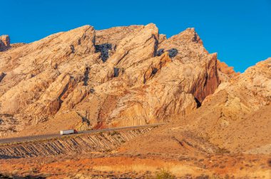 Bir yarı kamyon ve traktör I-70 boyunca uzanan engebeli Utah dağlarındaki bir dağ geçidinden geçmek için çok çalışıyor..