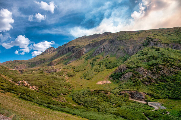Photograph of the beautiful lush landscape of Stony Pass in Colorado beneath summer skies with the smoke of nearby fires blowing in.