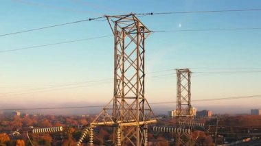 Altın saat günbatımında yüksek voltajlı elektrik kuleleri. İletişim güç hattı ve şebeke altyapısı. Elektrik hattı yalıtıcıları ve kablolar. Enerji krizi ve yüksek doğalgaz ve petrol fiyatları kavramı.
