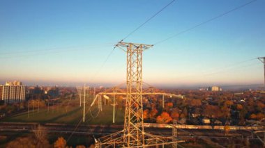 Altın saat günbatımında yüksek voltajlı elektrik kuleleri. İletişim güç hattı ve şebeke altyapısı. Elektrik hattı yalıtıcıları ve kablolar. Enerji krizi ve yüksek doğalgaz ve petrol fiyatları kavramı.