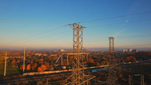 Altın saatinde kablolu iletişim kulesi. Elektrik direği ve yüksek voltajlı elektrik hattı altyapısı. Elektrikli araba şarjı veya EV aracı için elektrik şebekesinden elektrik iletimi