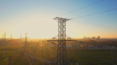 Altın saat arka planında yüksek voltajlı elektrik direği. Uluslararası Dünya Saati WWF etkinliği ya da elektrik kesintisi konsepti. Elektrikli araç veya EV kullanımına bağlı yüksek hidroelektrik güç talebi. 