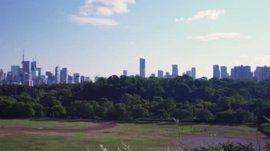 Toronto 'nun panoramik manzarası gün batımında Ontario Gölü' nün yakınında dağınık bulutlarda yükseliyor. Riverdale Park 'ta oynayan insanlar. Sıcak yaz gününde Toronto silueti. Toronto, Ontario, Kanada.