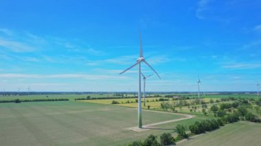 Açık mavi gökyüzü ve kırsal bölgedeki çiftçi tarlalarıyla enerji üretimi için güçlü rüzgar türbinlerinin havadan görünüşü. Yel değirmeni ya da rüzgar türbinleri çiftliği. Rüzgar gücü yel değirmenleri temiz sürdürülebilir enerji üretiyor