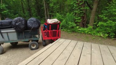 Camping cart on wheels at near camp cabin. Camping wagon with camping gear and equipment at national park tour in the forest. Cart containing sleeping bags for tent, portable freezer.