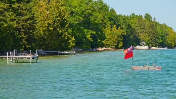 マニトーリン島のリゾートウォーターに位置する旗やスイミングラフト付きのスイミングプラットフォーム 明るい夏の日に安全な水泳や様々なレクリエーション活動のためのスペース — ストック動画