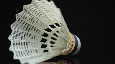 Badminton top ya da top plastikten yapılmıştır. Spor malzemelerinin bir parçası. Yaz oyunu ve hobi. Macro siyah arkaplan ve sığ alan derinliği üzerinde mekik horozunu kapat.