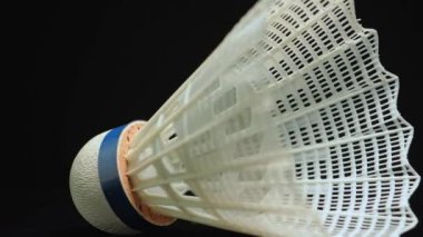 Badminton top ya da top plastikten yapılmıştır. Spor malzemelerinin bir parçası. Yaz oyunu ve hobi. Macro siyah arkaplan ve sığ alan derinliği üzerinde mekik horozunu kapat.